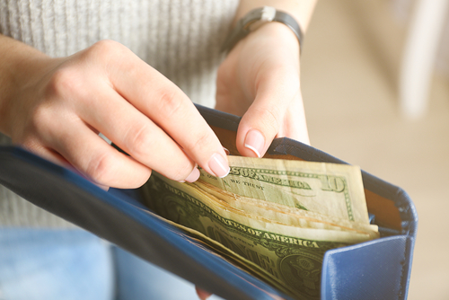 Woman counting money from blue wallet