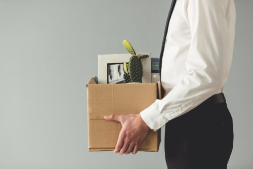 Man being fired and taking his desk belonging out of the office in a box