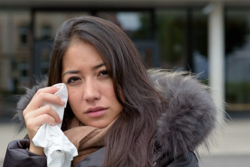 Woman wiping corner of her eye with a tissue
