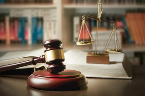 Gavel with scales of justice on a table with books in the background