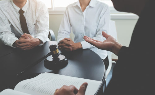 Three people sitting at a table with a gavel on the table