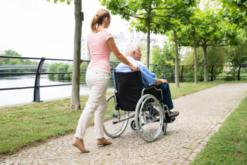 Woman pushing a man in a wheelchair through a park