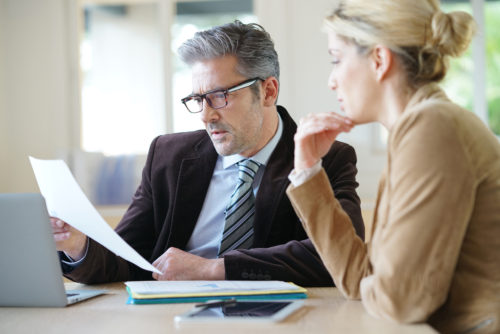 Older man and young woman looking at paperwork at a desk