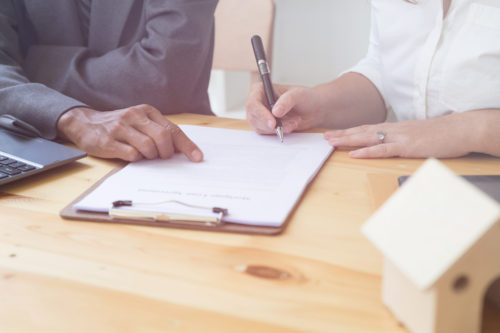 Man explaining legal paperwork to another man while he signs it