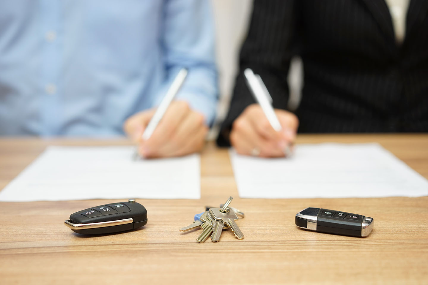 Men signing paperwork with silver pens