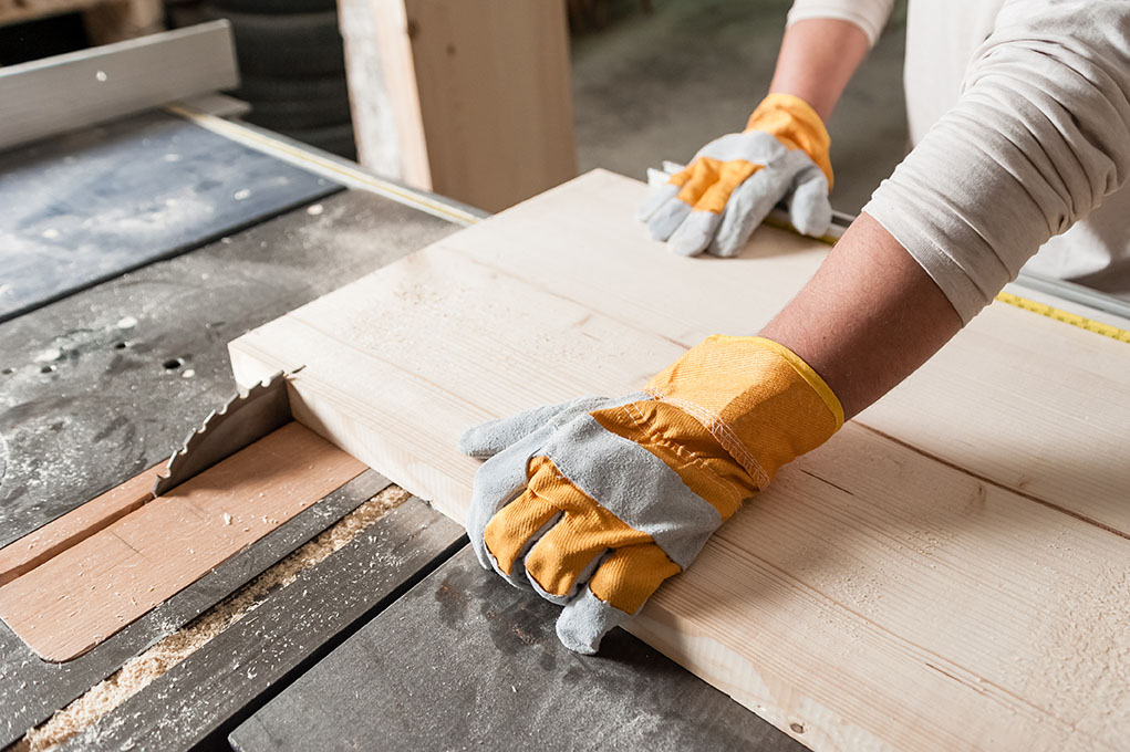 Close up of man's hands while he cuts wood with a circular saw