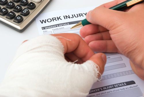 close up of man's injured hands while he fills out a workers comp form 