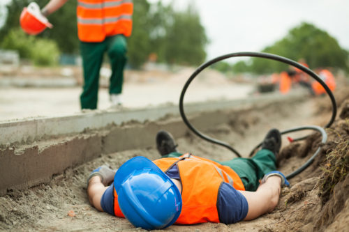 Construction worker hurt on the job and laying on his back in a ditch