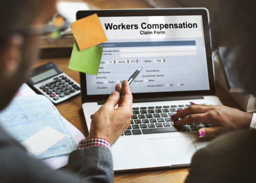 Man and woman filling out workers Compensation forms on a laptop