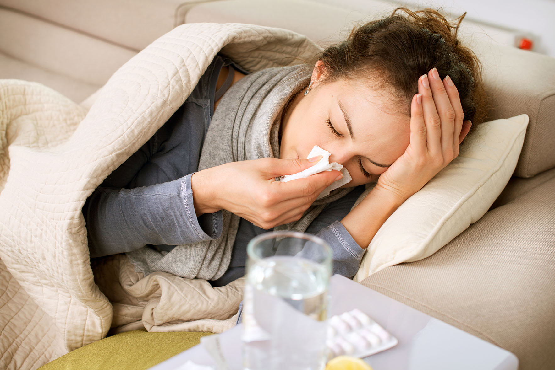 Lady on couch blowing nose