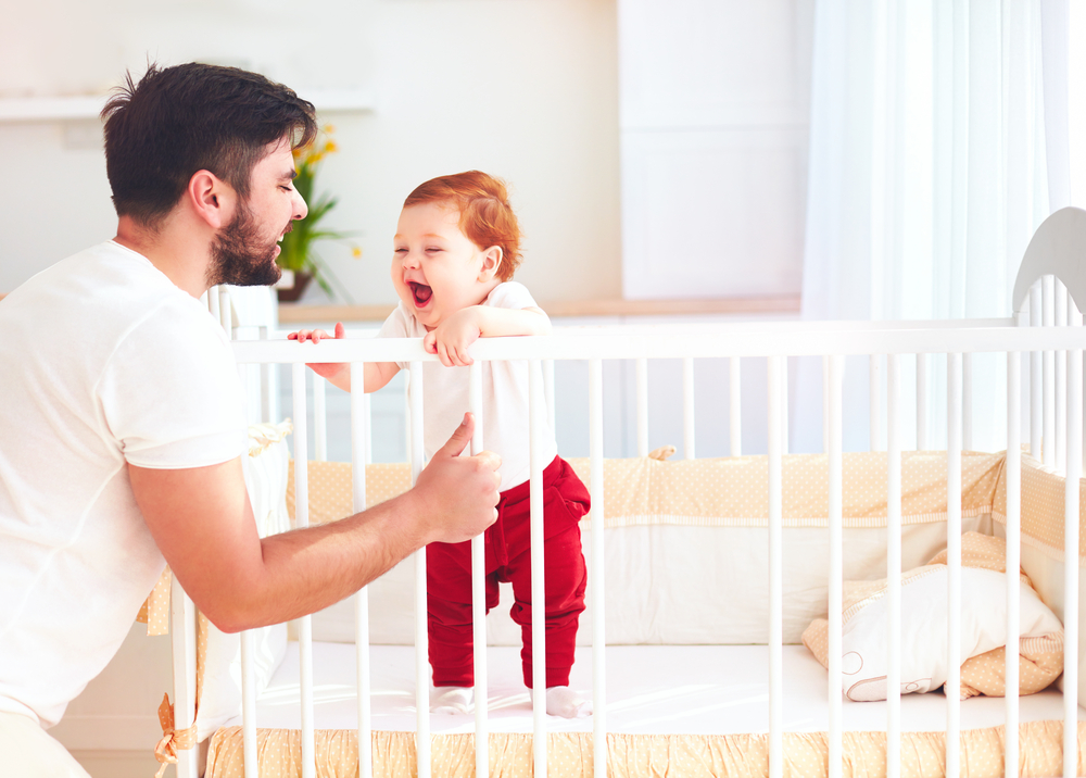Father tending to baby in a crib 