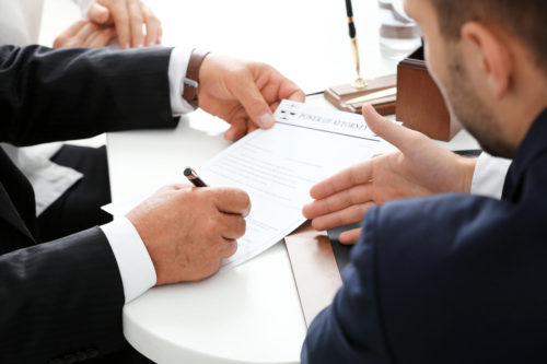 Man explaining legal paperwork to another man while he signs it