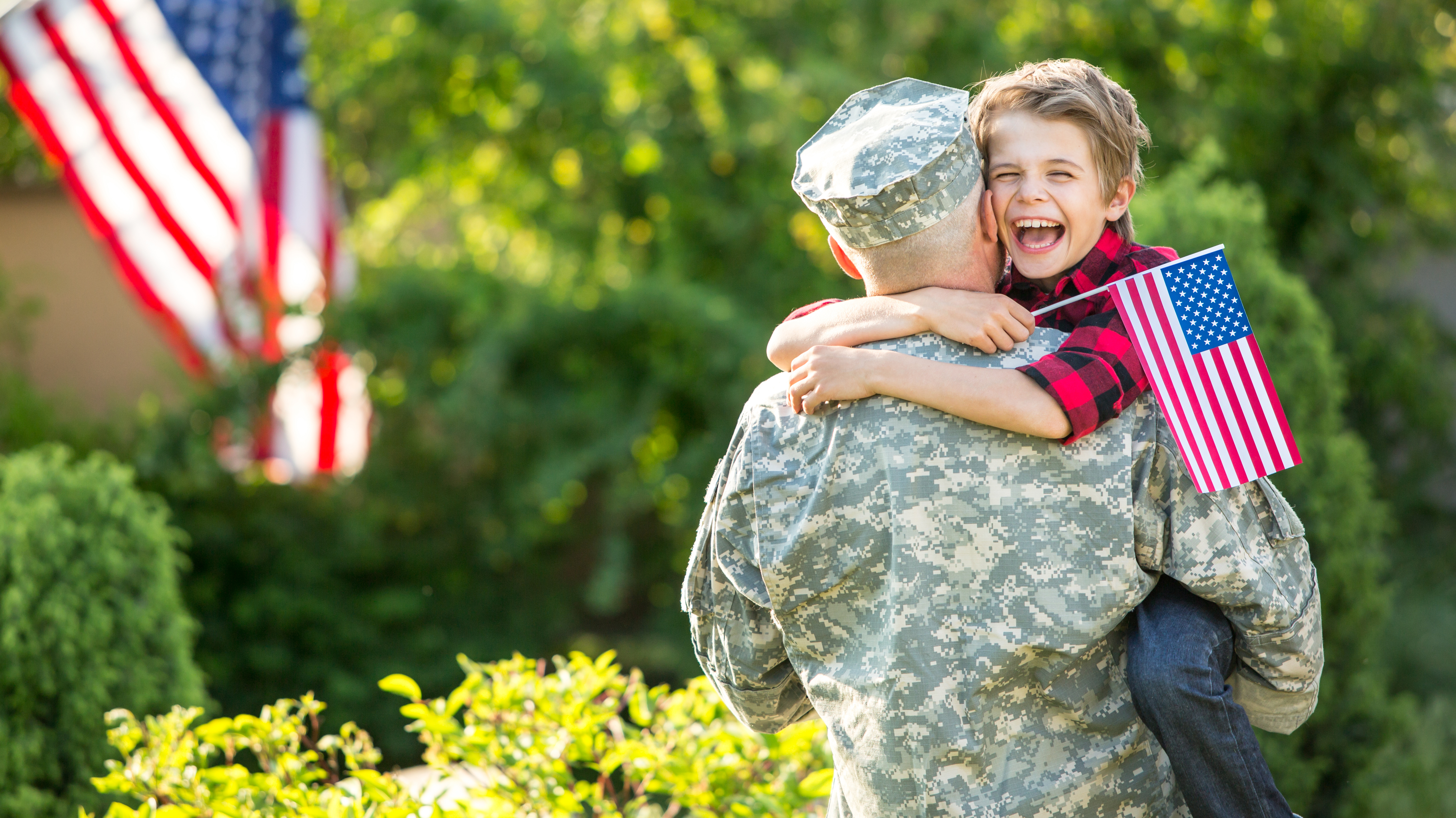 man in military uniform facing away from camera holding smiling child