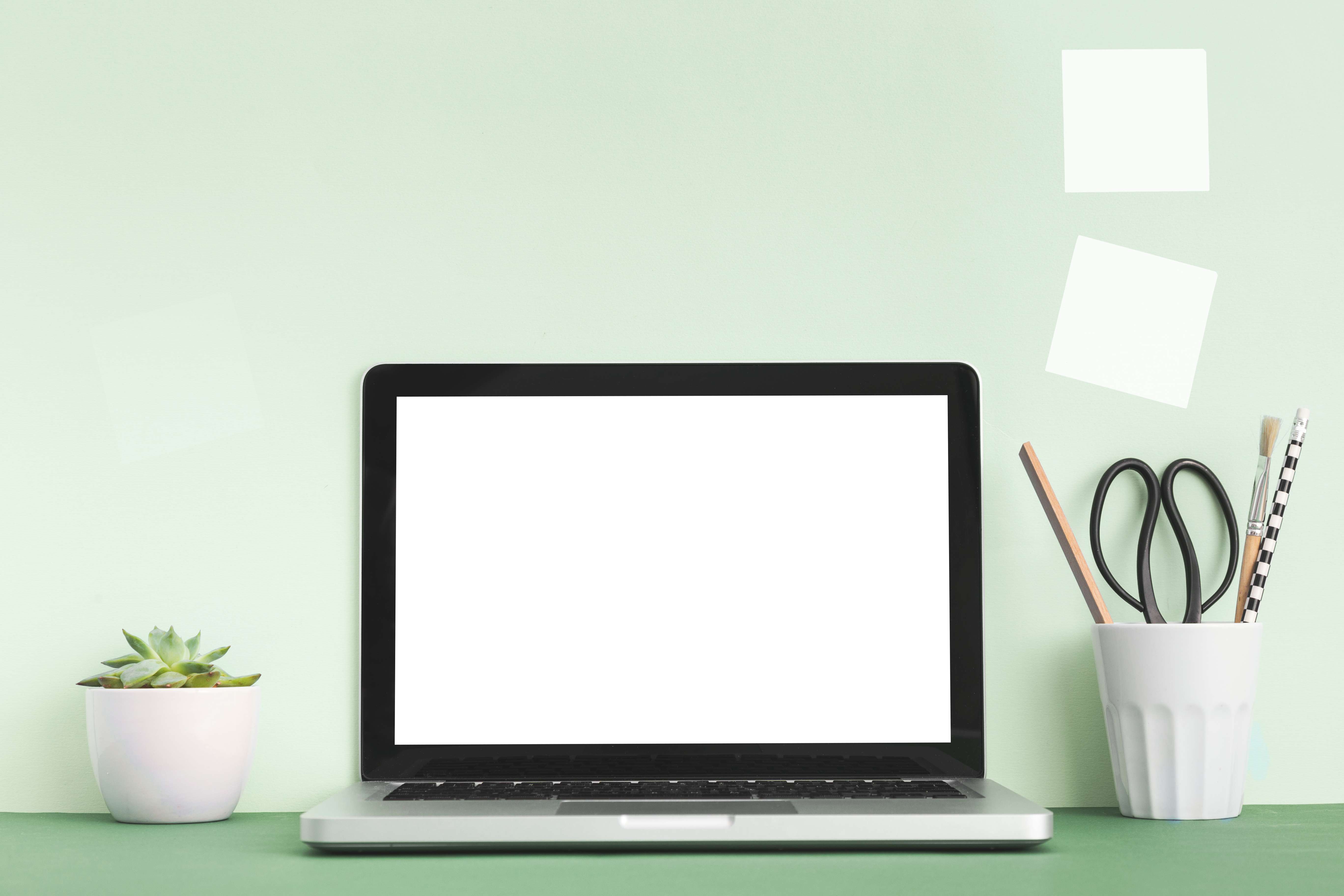 Computer with blank screen on a green desk and green background 