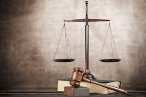 Gavel on table with eyeglasses atop a book in the background