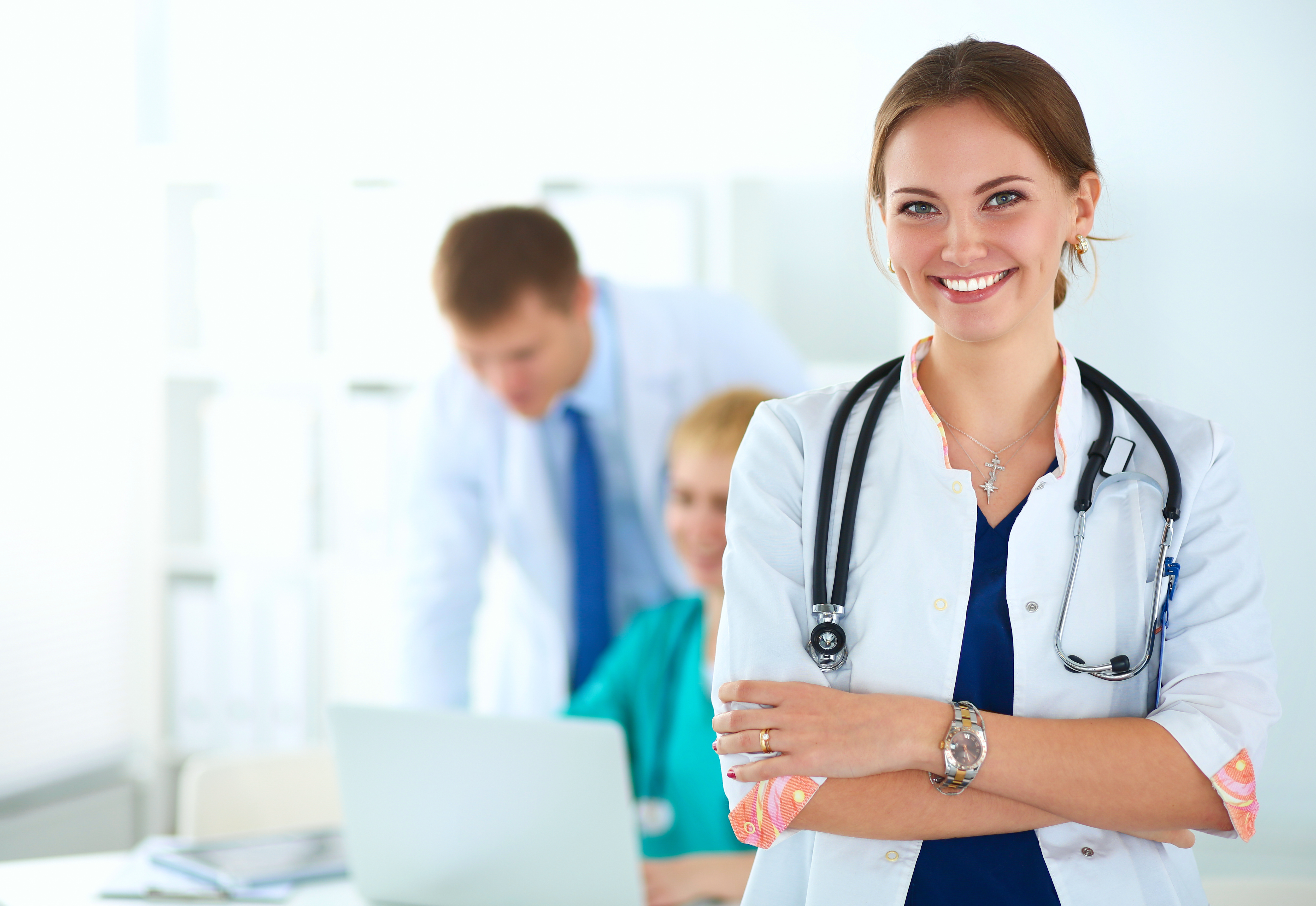 Smiling female doctor with coworkers in the background