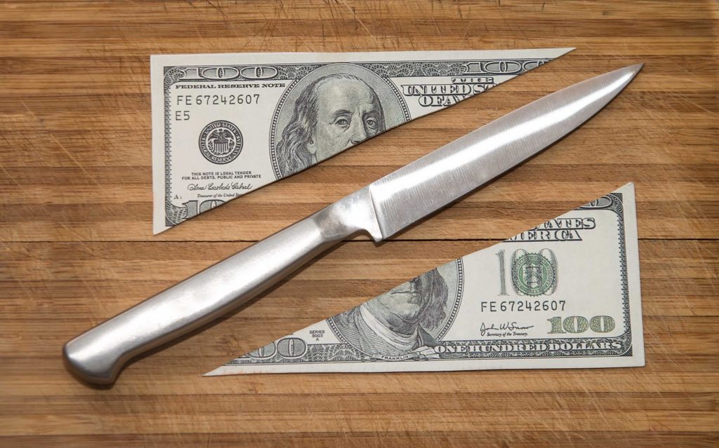 Hundred dollar bill cut diagonally with knife