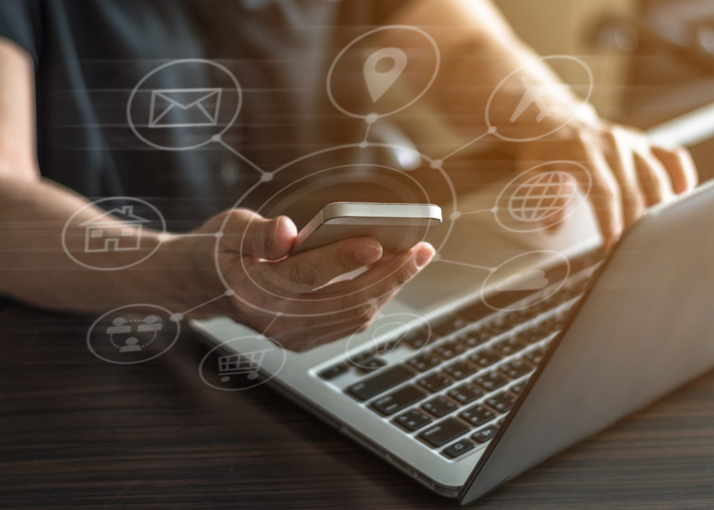 Man on phone and laptop with graphics displaying tech and connectivity