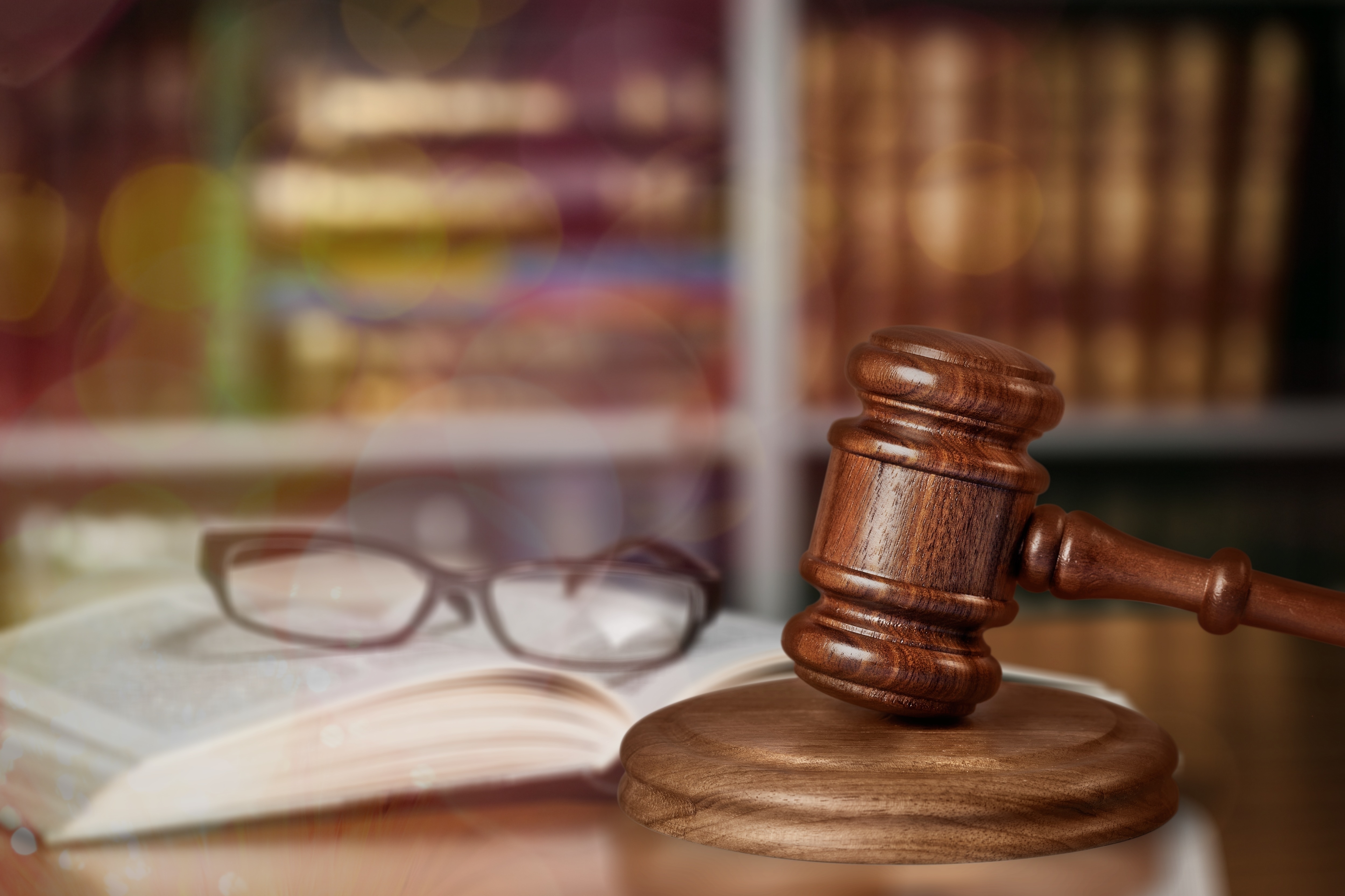 Gavel on table with eyeglasses atop a book in the background