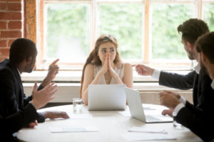 Young professional women being accosted by businessmen at a conference table 